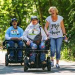 2 Frauen mit E-Rolli nehmen mit ihrer Begleitperson an einem Erlebnisrennen teil.