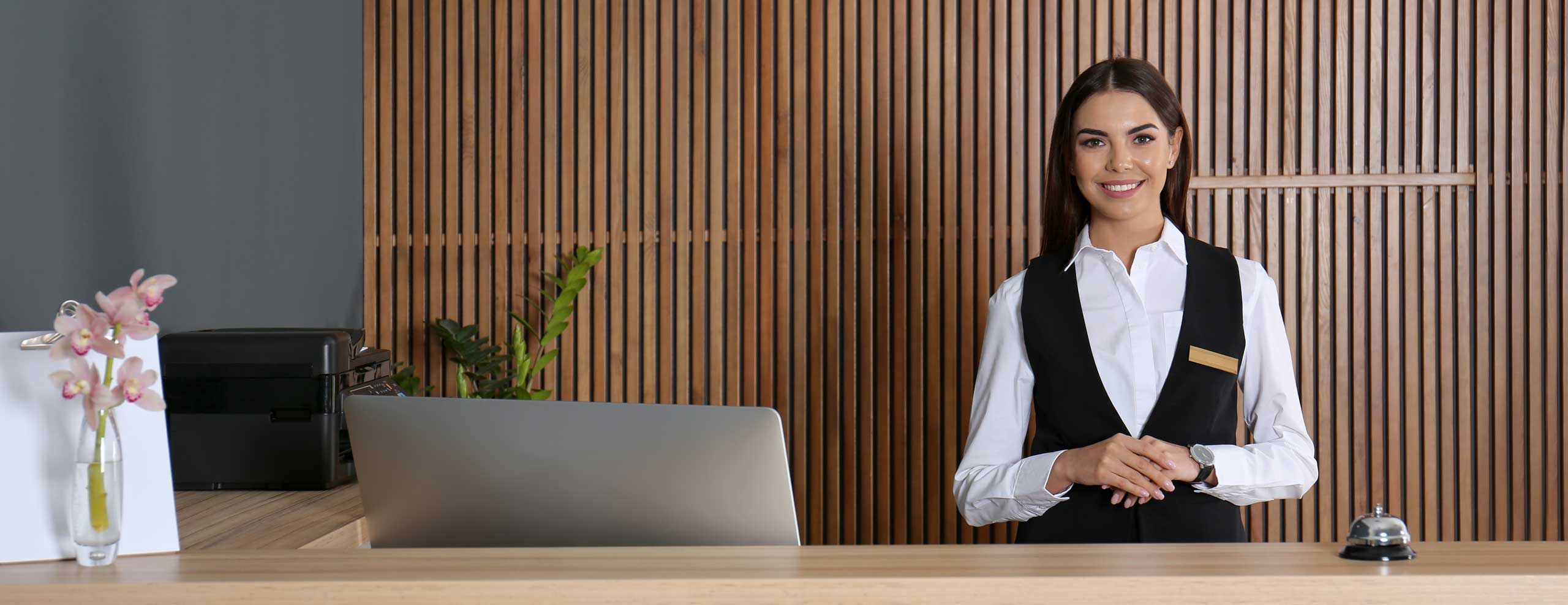 Portrait einer jungen Rezeptionistin am Schreibtisch in der Hotellobby