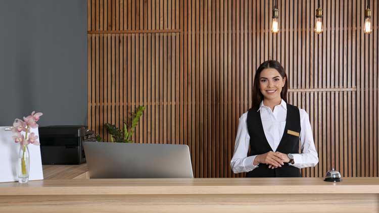 Portrait einer jungen Rezeptionistin am Schreibtisch in der Hotellobby