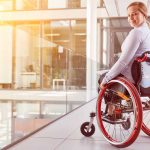 Junge Frau im Rollstuhl blickt lächelnd nach hinten